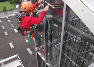 Fassadenkletterer reinigt Glasfront am hängenden Seil, Seilarbeit